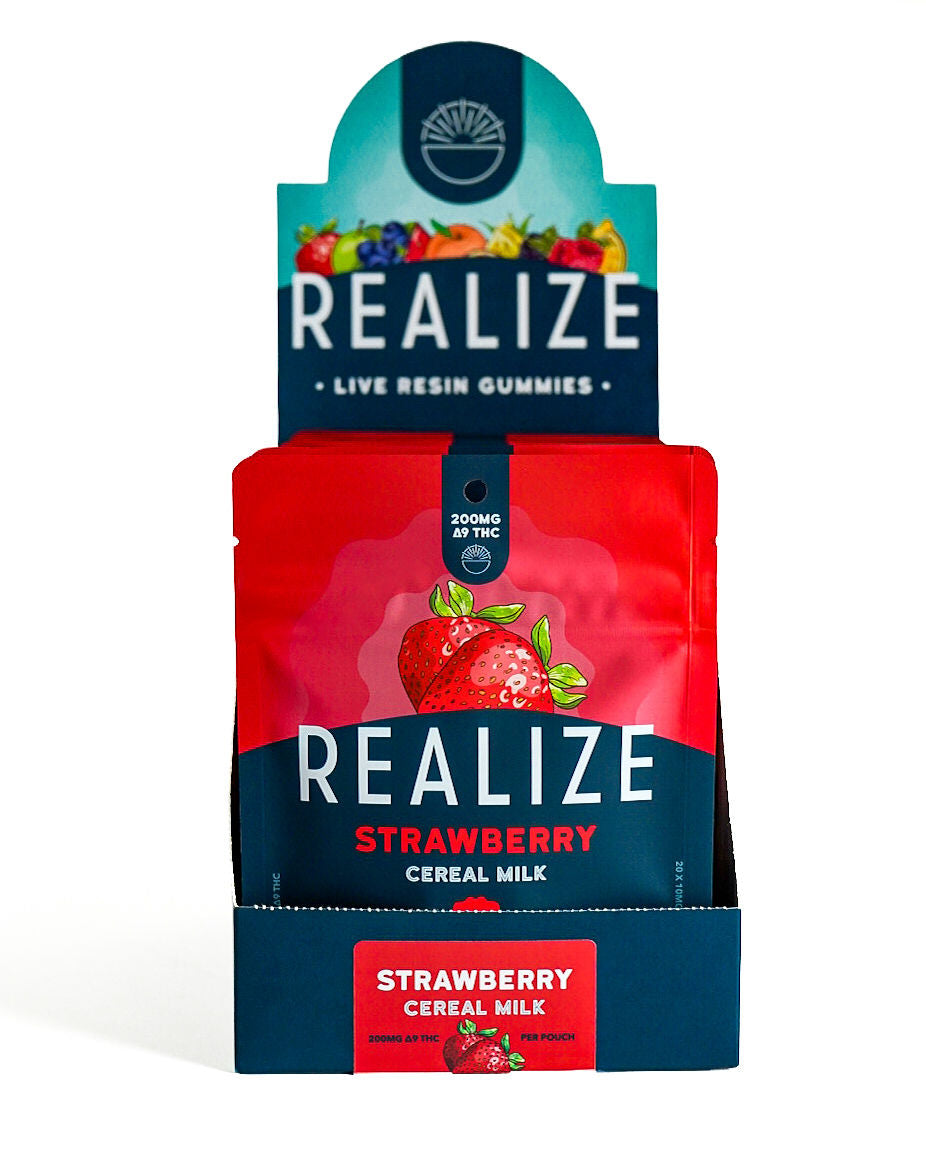 Wholesale display box featuring Realize Live Resin Gummies in Strawberry Cereal Milk flavor. The display contains bright red 200mg Δ9 THC gummy pouches with a strawberry illustration and Realize branding, presented in a navy countertop display with matching Strawberry Cereal Milk product label.